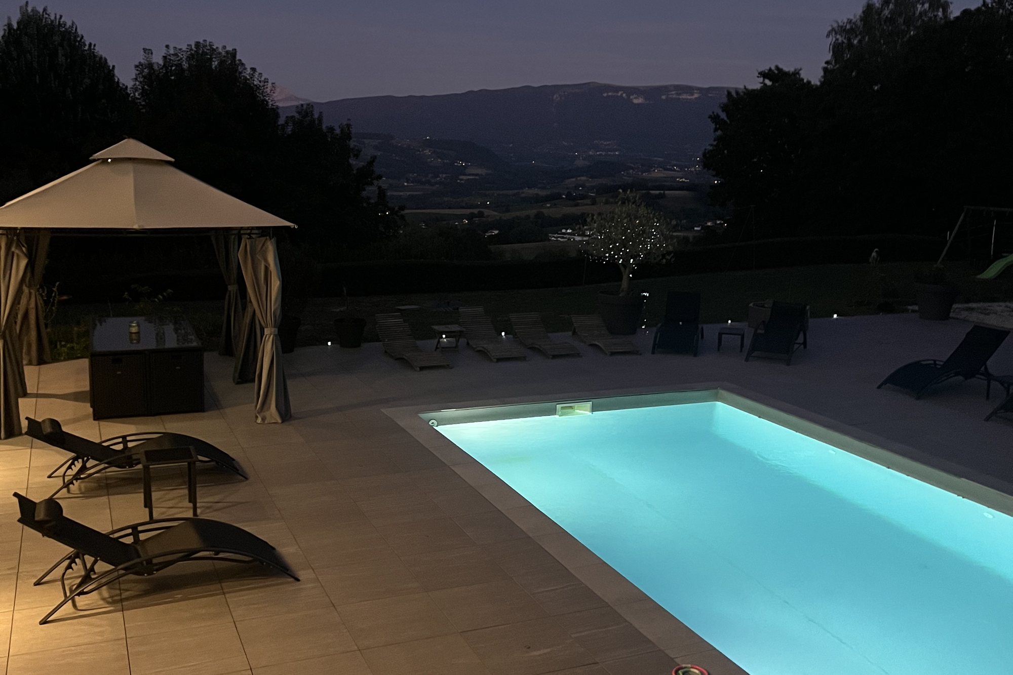Piscine chauffée illuminée la nuit, face à la vallée
