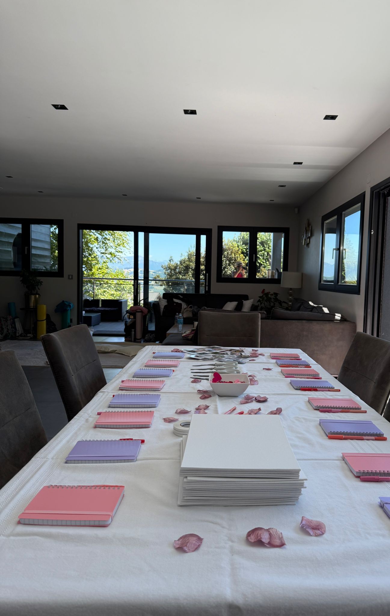 Grande table d'atelier dressée dans le séjour de la villa, vue sur les Alpes