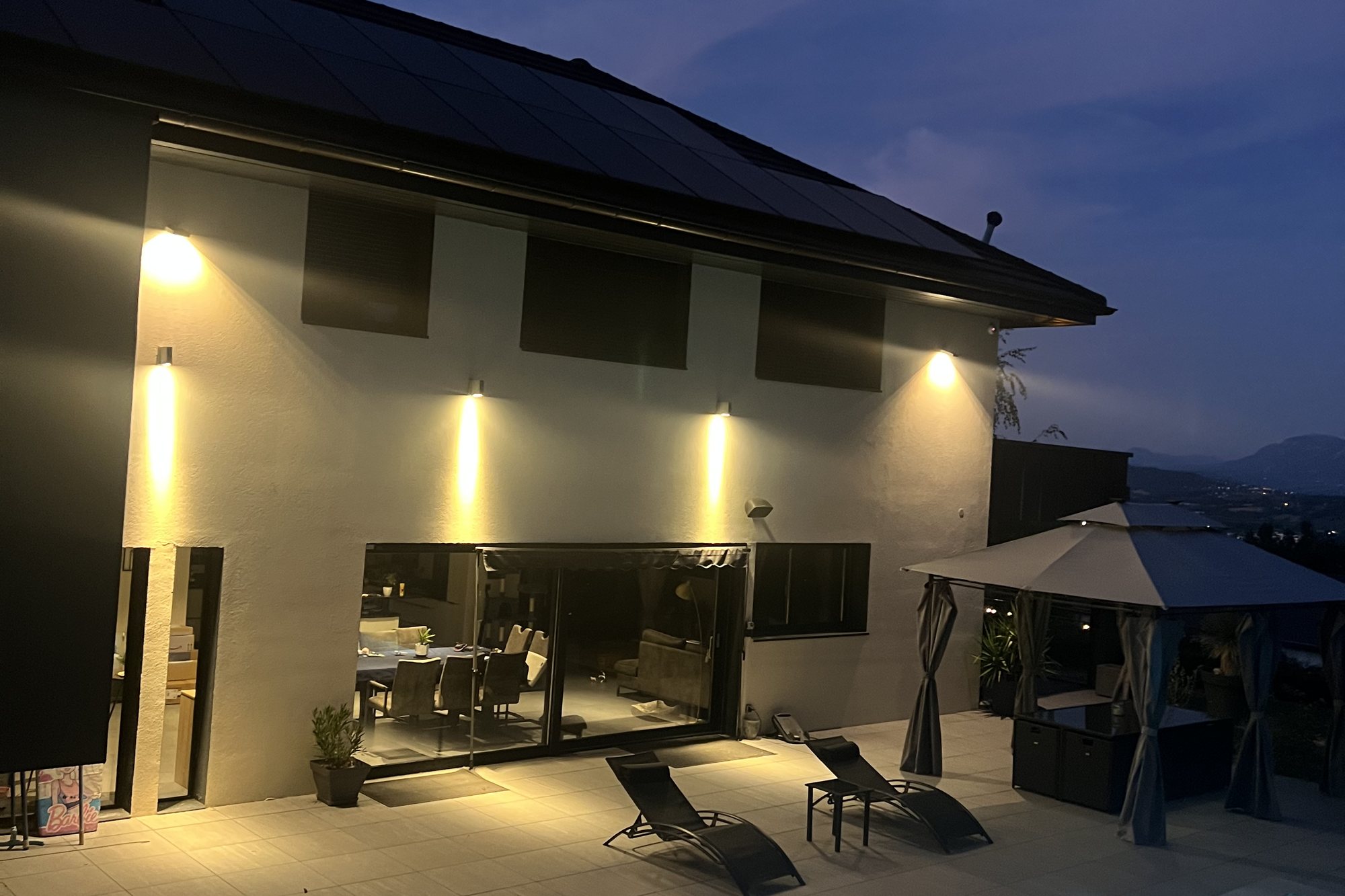 La villa et sa piscine éclairées à la tombée de la nuit